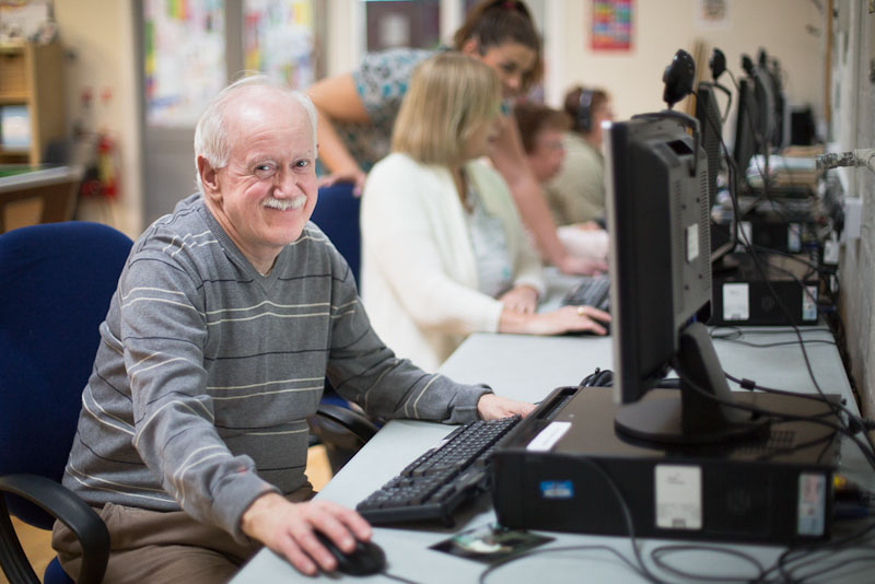 Old man smiling by the computer